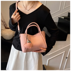 Détail du sac seau rose grainé avec breloque coeur et ferrures en métal argenté