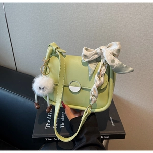 Détail du sac à bandoulière vert avec pendentif en peluche et foulard en soie