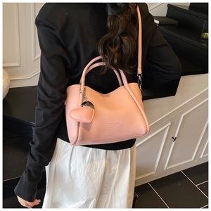 Sac seau rose texture litchi avec pendentif coeur et une bandoulière fine pour le quotidien