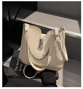 Detailed close-up of cream crocodile pattern leather bag with silver buckle and chain