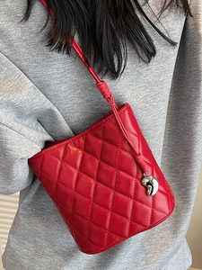 Sac seau matelassé rouge à motif losanges avec pendentif argenté et bandoulière chic