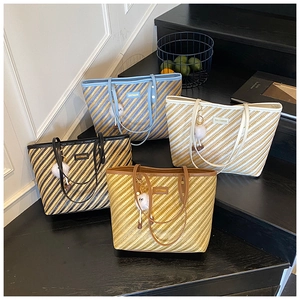 Group shot of striped tote bags in four colors with plush charms on dark stairs