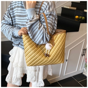 Close-up of woven tote bag with herringbone pattern and cute plush charms on model