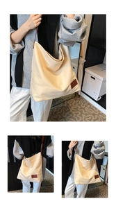 Detail of the large canvas tote bag featuring brown leather straps and minimal design