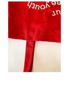 Detail of red canvas tote bag with white free youth embroidery and X-shaped stitching
