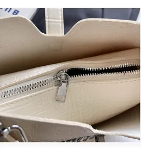 Detail of smooth silver zipper and interior lining of white crocodile pattern shoulder bag