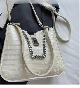 Close-up of cream faux crocodile texture with silver twist lock and chain strap detail