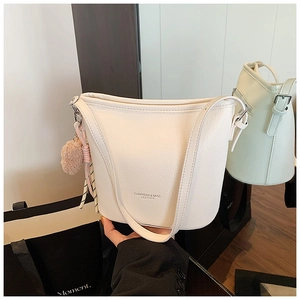 Dettaglio borsa a secchiello bianca in pelle litchi con pompon rosa e nastro seta