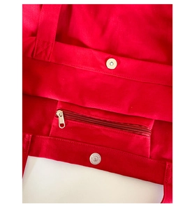 Detail view of the red canvas tote bag interior with a zipper pocket and magnetic snap