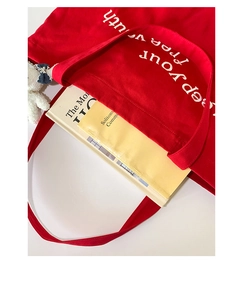 Detail of red canvas tote bag featuring white letter embroidery and cute bear keychain