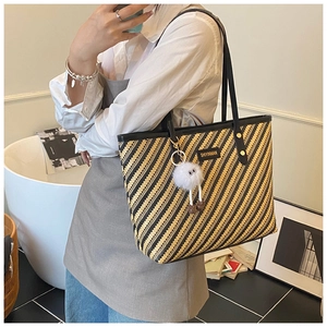 Detail of striped woven tote bag with leather trim and plush eyeball pendant