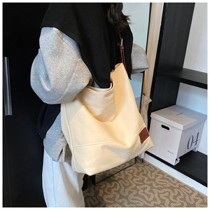 Detail view of large canvas tote bag in cream white with a brown leather logo patch