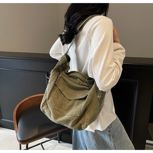 Detail view of olive green canvas shoulder bag with distressed frayed hole design and pocket