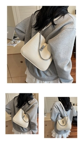 Detail view of cream shoulder bag with crocodile texture and silver chain strap