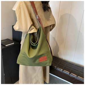 Detail of army green canvas hobo bag with brown leather strap and decorative leather patch