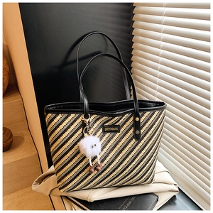 Close-up of large woven tote bag with black and yellow diagonal stripes and leather handles