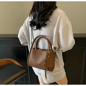 Détails du sac seau en cuir marron avec pendentif chien et inscription mode élégante