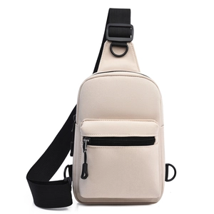 Detail of beige canvas crossbody chest bag featuring a front zipper pocket and black strap