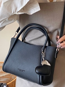 Sac seau en cuir noir avec pendentif cœur et bandoulière réglable sur un mannequin
