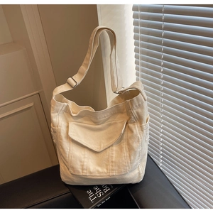 Detail of minimalist cream canvas tote bag with adjustable wide strap and front flap pocket