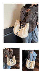 Close-up detail of large canvas tote bag with blue Teln lettering and brown leather strap