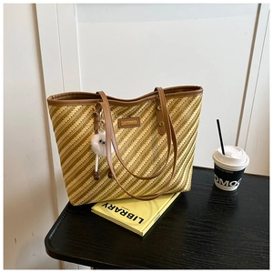 Detailed close-up of woven straw tote bag texture with leather trim and plush charm