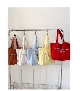 Row of colorful canvas tote bags hanging on rack showing five different vibrant colors