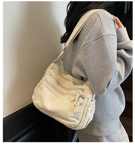 Detail of off-white canvas bag with multiple zipper pockets and adjustable strap