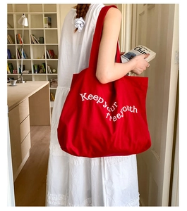 Close-up of red canvas tote bag with white Keep your Free youth letter embroidery