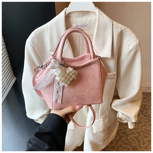 Dettaglio borsa a secchiello rosa con ciondolo a cuore di perle e nastro di pizzo