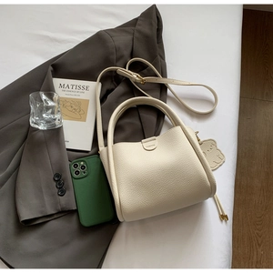 Sac seau chic en cuir beige avec étiquette mode et détail de charmant petit ours