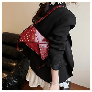 Fashionable wine red studded crossbody bag shown on a shoulder in a modern indoor setting