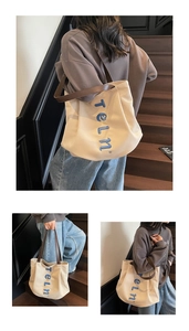 Detail of canvas tote bag showing blue 3D embroidery and sturdy brown PU leather handles
