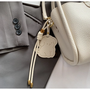 Détail du sac à main blanc en cuir grainé avec breloque chien et finitions dorées