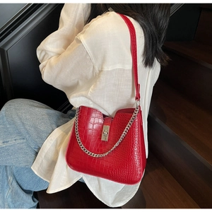 Detail view of red crocodile pattern bucket bag with silver chain and metal lock