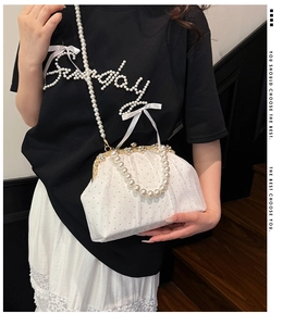 Detail of white pleated fabric evening bag with pearl handle and metal clasp closure