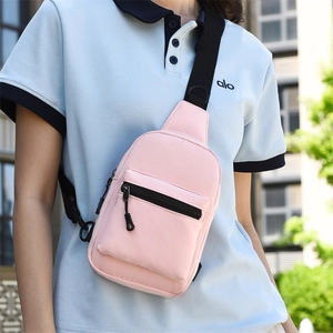 Pink canvas crossbody chest bag detail featuring black nylon strap and front zipper pocket