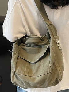 Olive green canvas messenger bag with large front pocket and frayed tassel edges