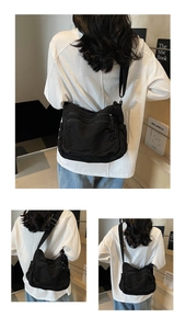 Detail showing back view of black canvas messenger bag with multiple zipper pockets
