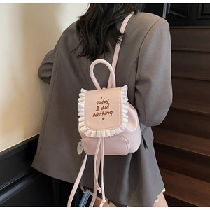 Dettaglio di un mini zaino rosa chiaro con ricamo e bordi decorativi a volant
