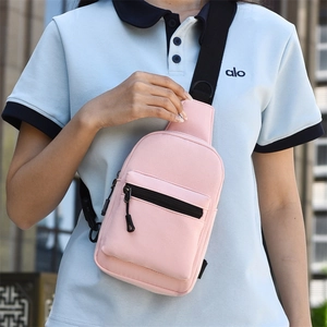 Close-up of pink crossbody bag with durable fabric, dual zippers and wide black strap