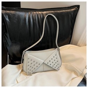 Close-up of cream shoulder bag with decorative silver metal studs and sleek leather finish
