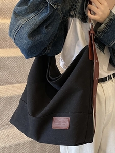 Minimalist black canvas tote bag with brown leather straps and square logo patch