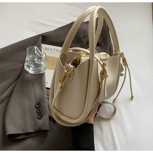 Détail du sac seau en cuir texturé blanc cassé avec ferrures dorées et cordon de serrage