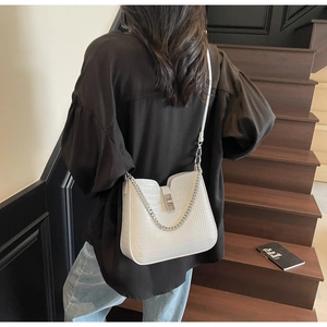 Detail of cream crocodile embossed crossbody bag with silver twist lock and metal chain