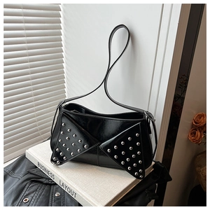 Detail of black glossy leather shoulder bag with silver rivet studs and geometric flap