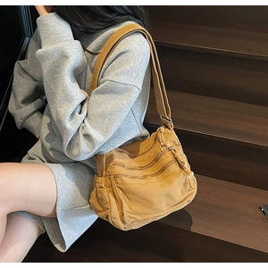 Detail showing ginger yellow canvas crossbody bag with multiple front zipper pockets and strap
