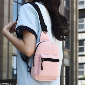Pink canvas crossbody chest bag shown from side-back view on a model in an urban setting