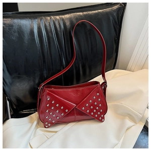 Close-up of vibrant red leather shoulder bag with glossy finish and silver metal rivets