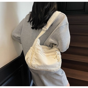 Detail of cream canvas crossbody bag with multi-zipper pockets in daily use setting